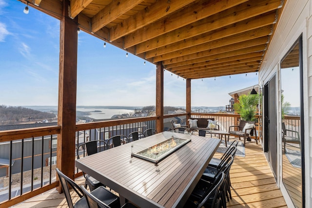 deck with a water view and an outdoor living space with a fire pit