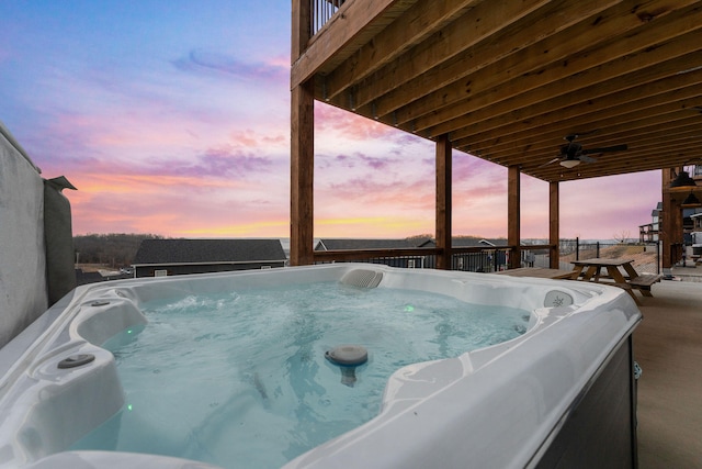 pool at dusk with ceiling fan and a hot tub