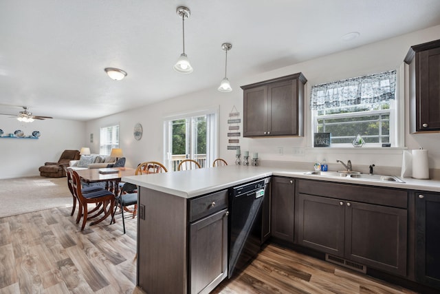 kitchen with light hardwood / wood-style floors, black dishwasher, dark brown cabinets, decorative light fixtures, and kitchen peninsula