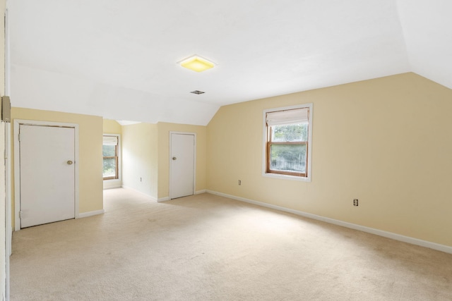 bonus room featuring baseboards, vaulted ceiling, and light colored carpet