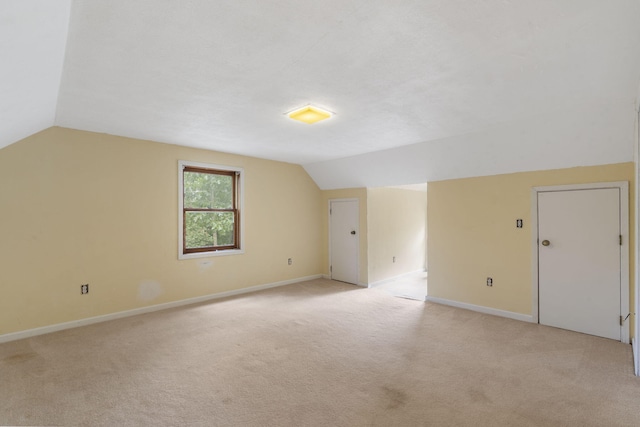 additional living space featuring baseboards, lofted ceiling, and light colored carpet