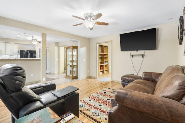 living room featuring a ceiling fan, baseboards, and light wood-style flooring