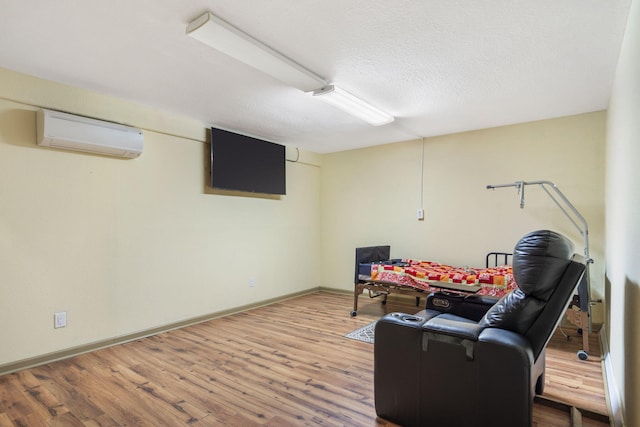 living area with wood finished floors, a textured ceiling, an AC wall unit, and baseboards