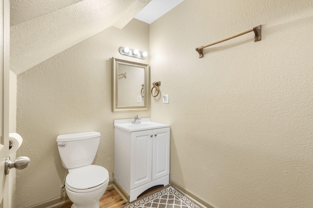 bathroom featuring vanity, lofted ceiling, and toilet