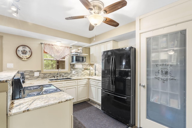 kitchen with light stone counters, backsplash, a ceiling fan, a sink, and black appliances
