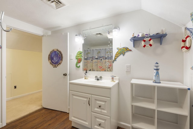 bathroom with lofted ceiling, vanity, wood finished floors, and visible vents