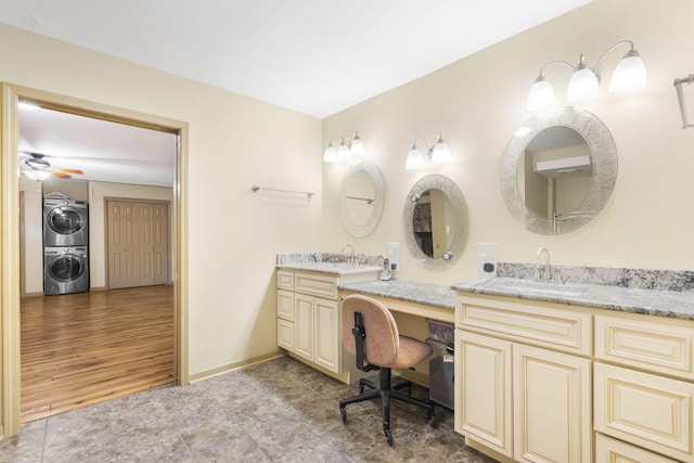 bathroom featuring double vanity, stacked washing maching and dryer, tile patterned flooring, and a sink