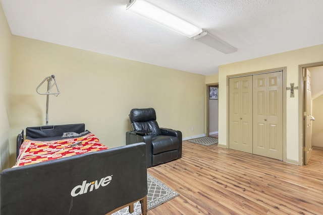 living area with baseboards, wood finished floors, and a textured ceiling