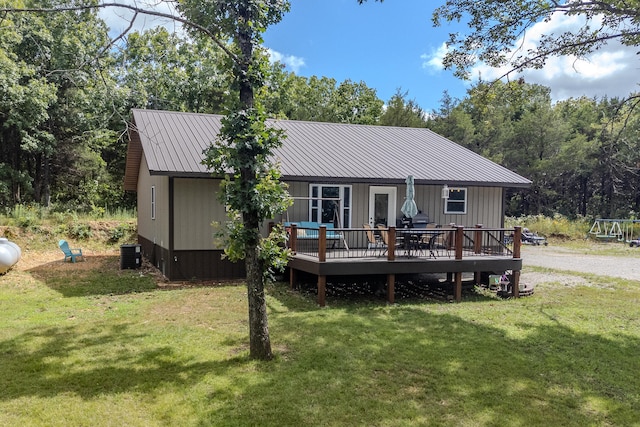 rear view of house featuring a deck, central air condition unit, and a lawn