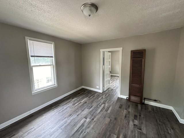 unfurnished room with a textured ceiling and dark hardwood / wood-style flooring