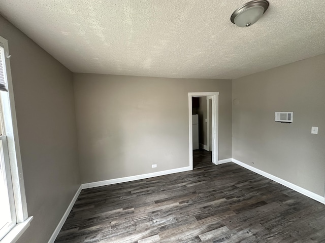 empty room featuring a textured ceiling and dark hardwood / wood-style flooring