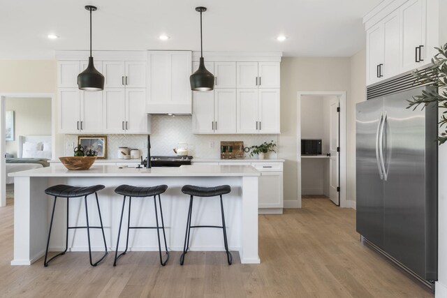 kitchen featuring white cabinets, light hardwood / wood-style floors, decorative light fixtures, and built in refrigerator