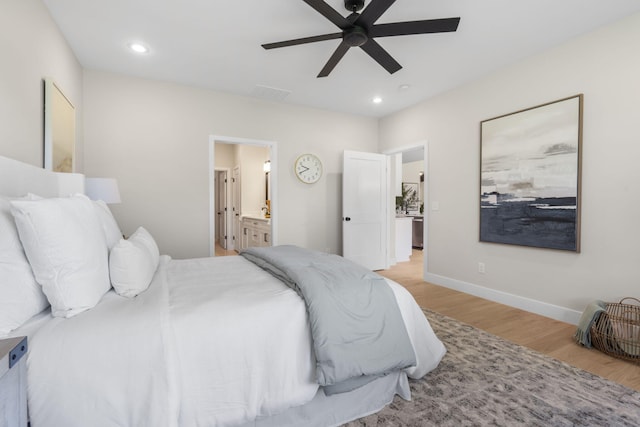 bedroom with light hardwood / wood-style floors, ceiling fan, and ensuite bath