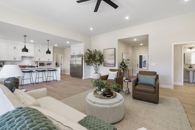 living room with light hardwood / wood-style floors, ceiling fan, and sink