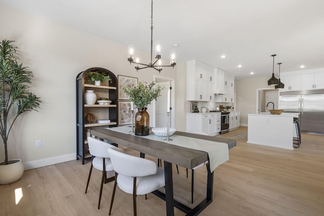 dining space featuring light wood-type flooring, sink, and a notable chandelier