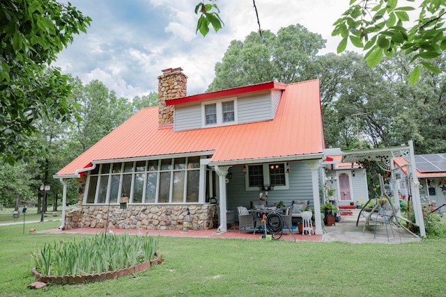 back of property with a lawn, a sunroom, and a patio area