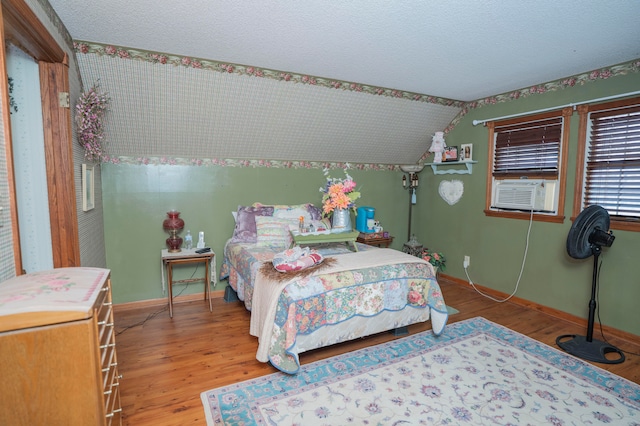 bedroom with hardwood / wood-style floors, cooling unit, a textured ceiling, and vaulted ceiling