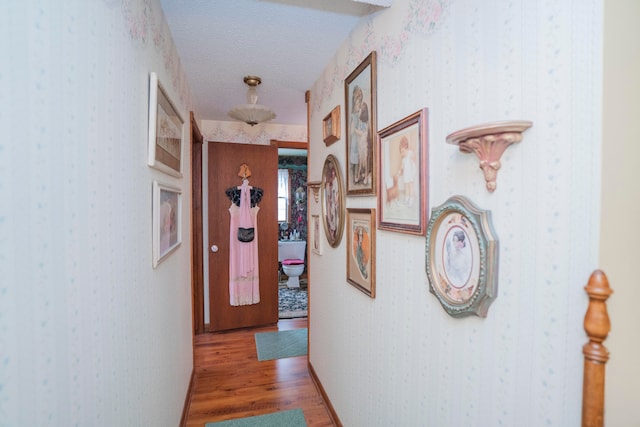 hall with hardwood / wood-style floors and a textured ceiling