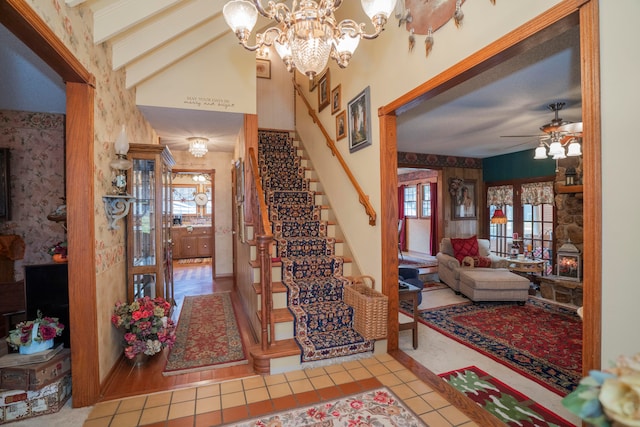 stairway with ceiling fan with notable chandelier, tile patterned floors, and beam ceiling