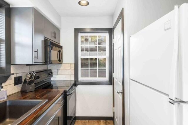 kitchen with decorative backsplash, black appliances, and light hardwood / wood-style flooring