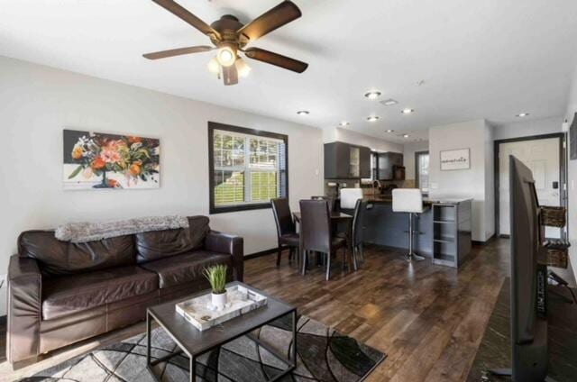 living room featuring dark wood-type flooring and ceiling fan