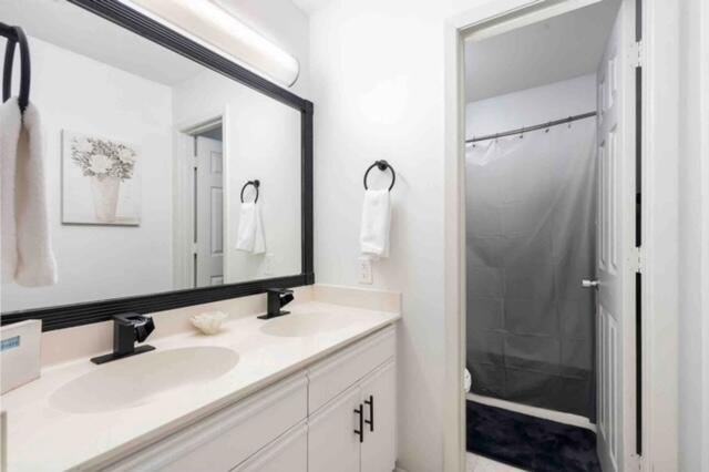 bathroom with a shower with shower curtain, vanity, and toilet