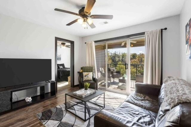 living room with ceiling fan and dark wood-type flooring