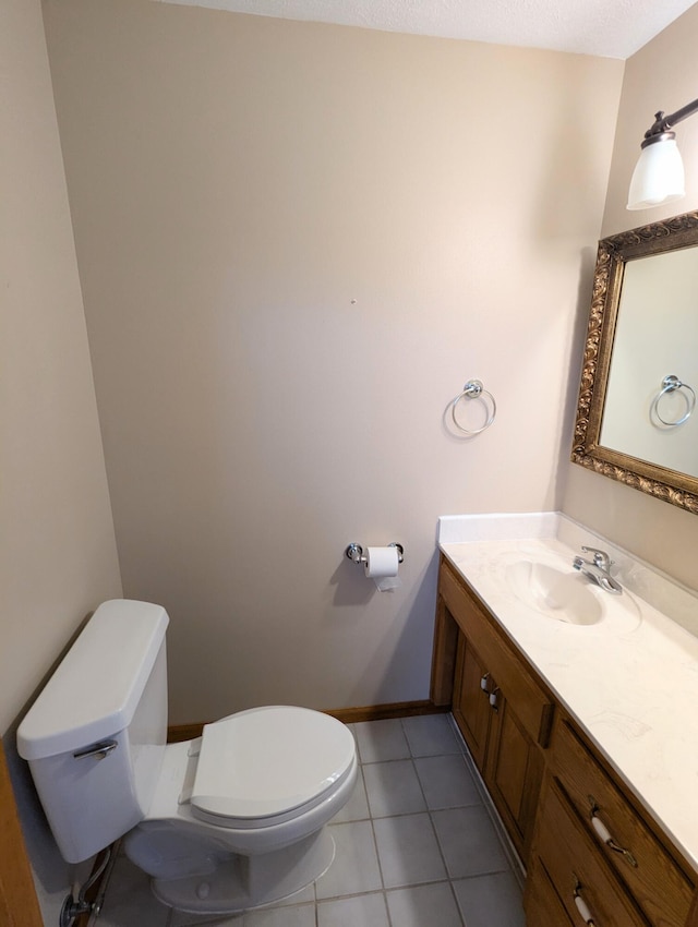 half bath with baseboards, toilet, vanity, and tile patterned floors