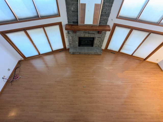 unfurnished living room featuring light wood-type flooring, a fireplace, and a towering ceiling