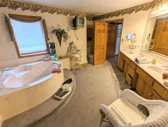 bathroom featuring toilet, a sink, double vanity, and a tub with jets