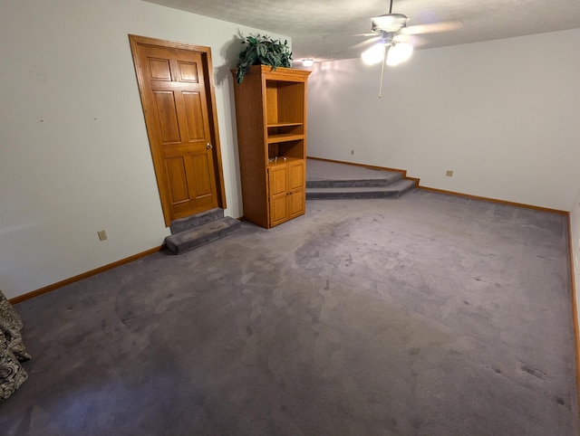 interior space with dark colored carpet, ceiling fan, and a textured ceiling