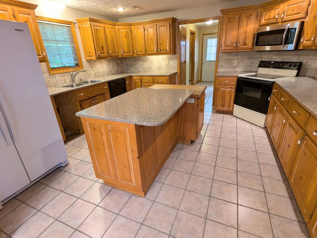 kitchen with range with electric cooktop, a sink, stainless steel microwave, freestanding refrigerator, and a center island