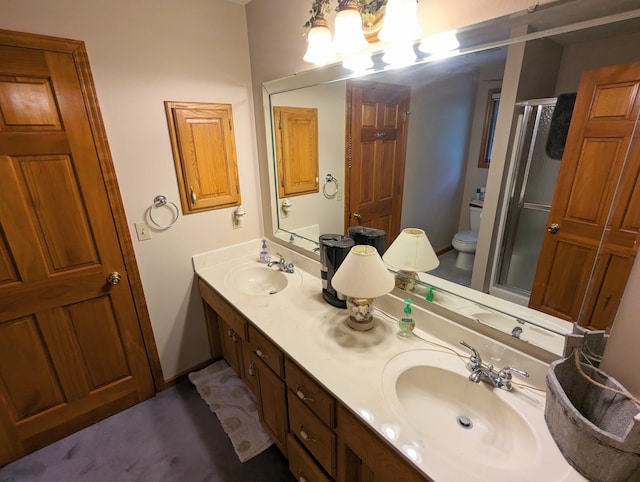 bathroom featuring toilet, a sink, double vanity, and a stall shower