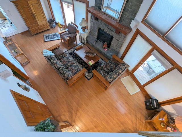 living room with a stone fireplace, hardwood / wood-style flooring, and a high ceiling