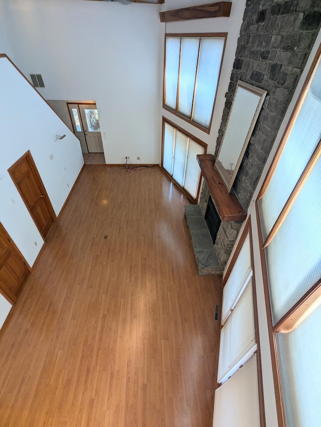 unfurnished living room with a fireplace, wood-type flooring, and a high ceiling