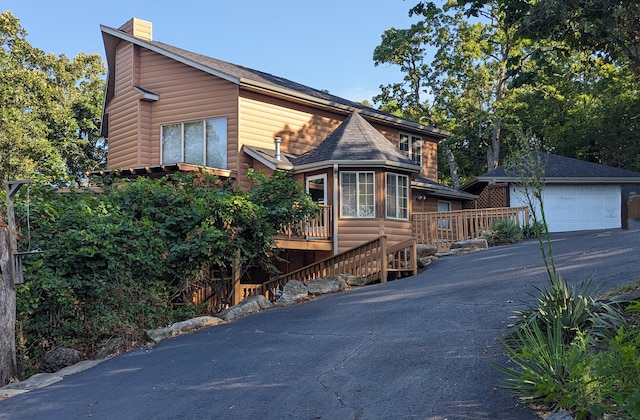 view of front of property with faux log siding, a deck, an outdoor structure, and a garage