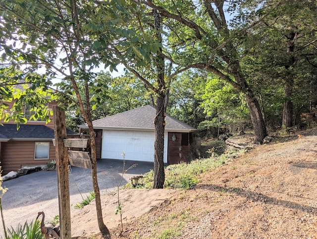 view of side of home featuring an outbuilding, roof with shingles, and a detached garage