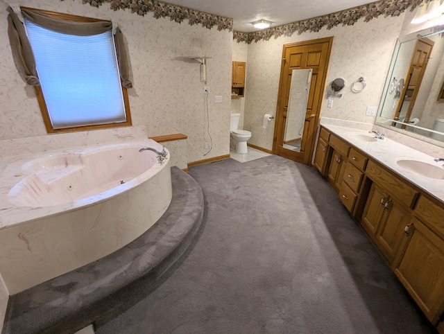 bathroom featuring double vanity, a jetted tub, toilet, and a sink