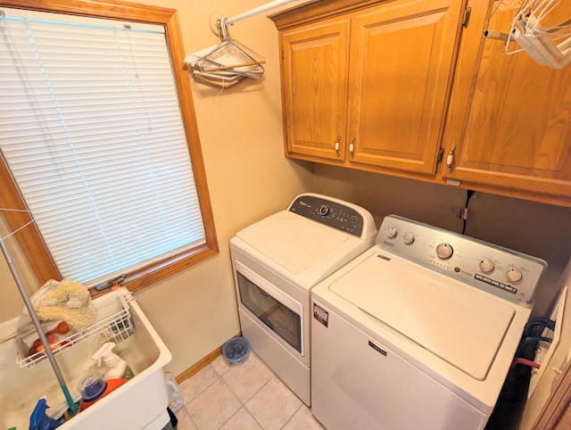 laundry area with cabinet space, baseboards, washer and dryer, and light tile patterned floors