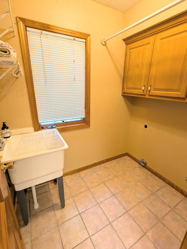 laundry room featuring baseboards, cabinet space, and light tile patterned floors