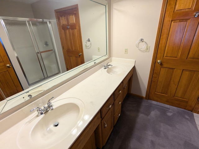 bathroom featuring baseboards, a sink, a shower stall, and double vanity