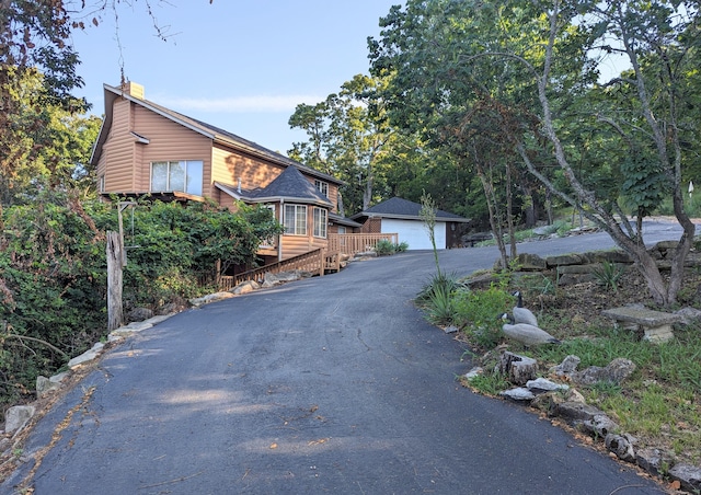 view of front of house featuring an outdoor structure, faux log siding, a chimney, and a garage