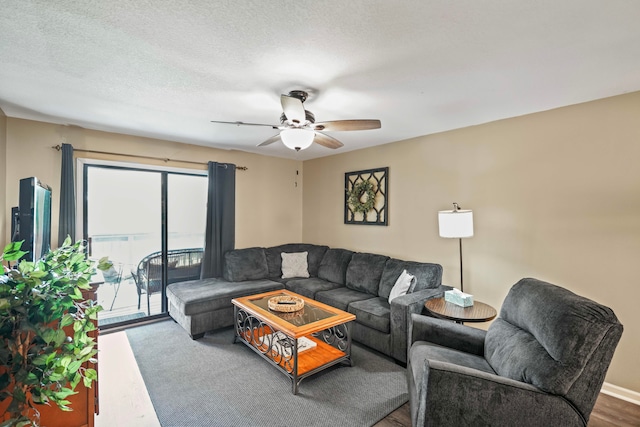 living room with ceiling fan, wood-type flooring, and a textured ceiling