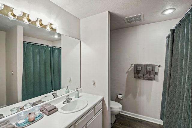 bathroom with vanity, toilet, wood-type flooring, and a textured ceiling