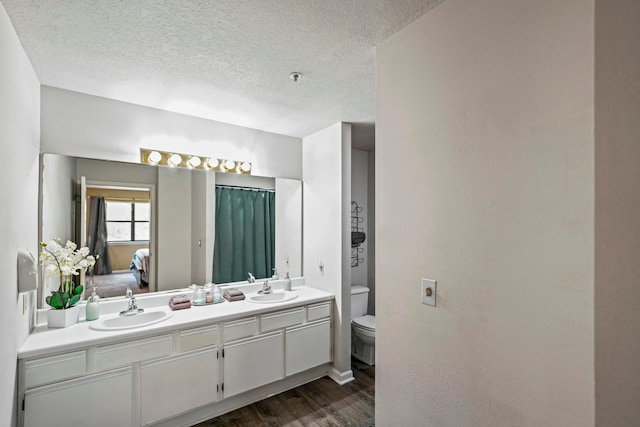 bathroom featuring a textured ceiling, hardwood / wood-style floors, vanity, and toilet