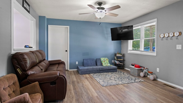 living room featuring ceiling fan, hardwood / wood-style flooring, and a textured ceiling