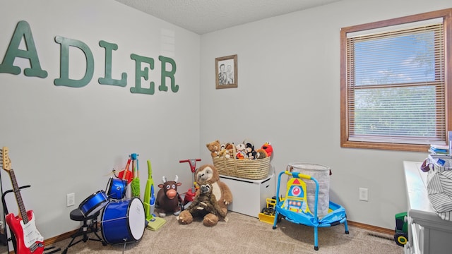 recreation room with a textured ceiling and carpet flooring