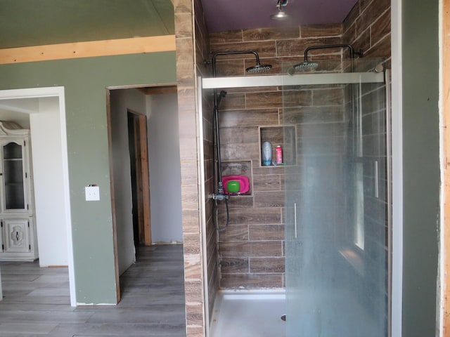 bathroom featuring a tile shower and wood-type flooring