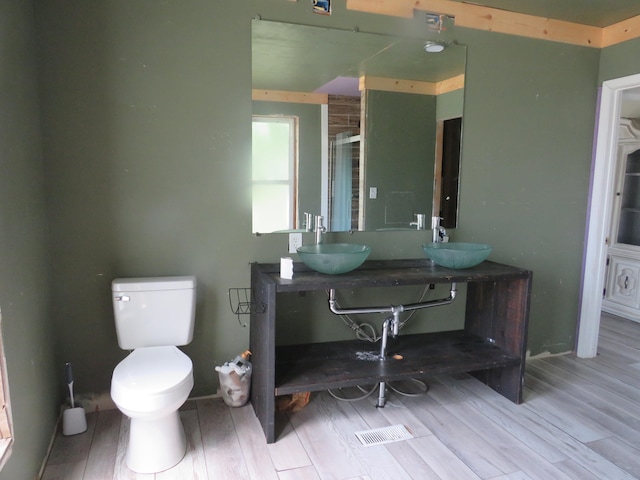 bathroom featuring hardwood / wood-style flooring, a shower with shower door, vanity, and toilet