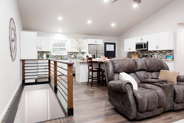 living area with recessed lighting, wood finished floors, lofted ceiling, and baseboards